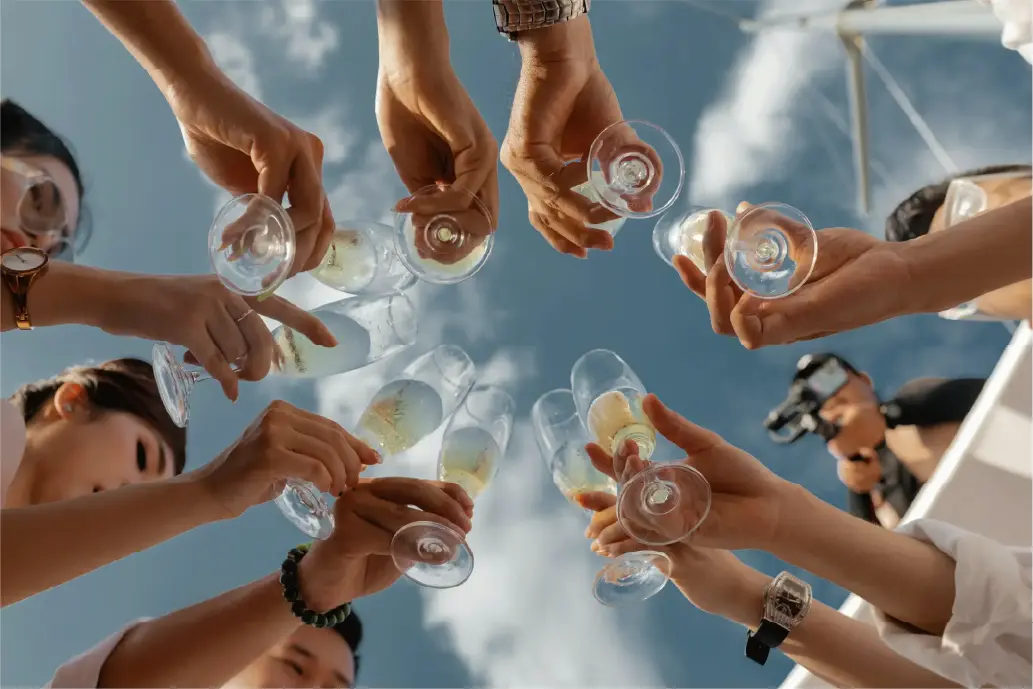 A group of people making a toast, shot from below with a clear blue sky in the background