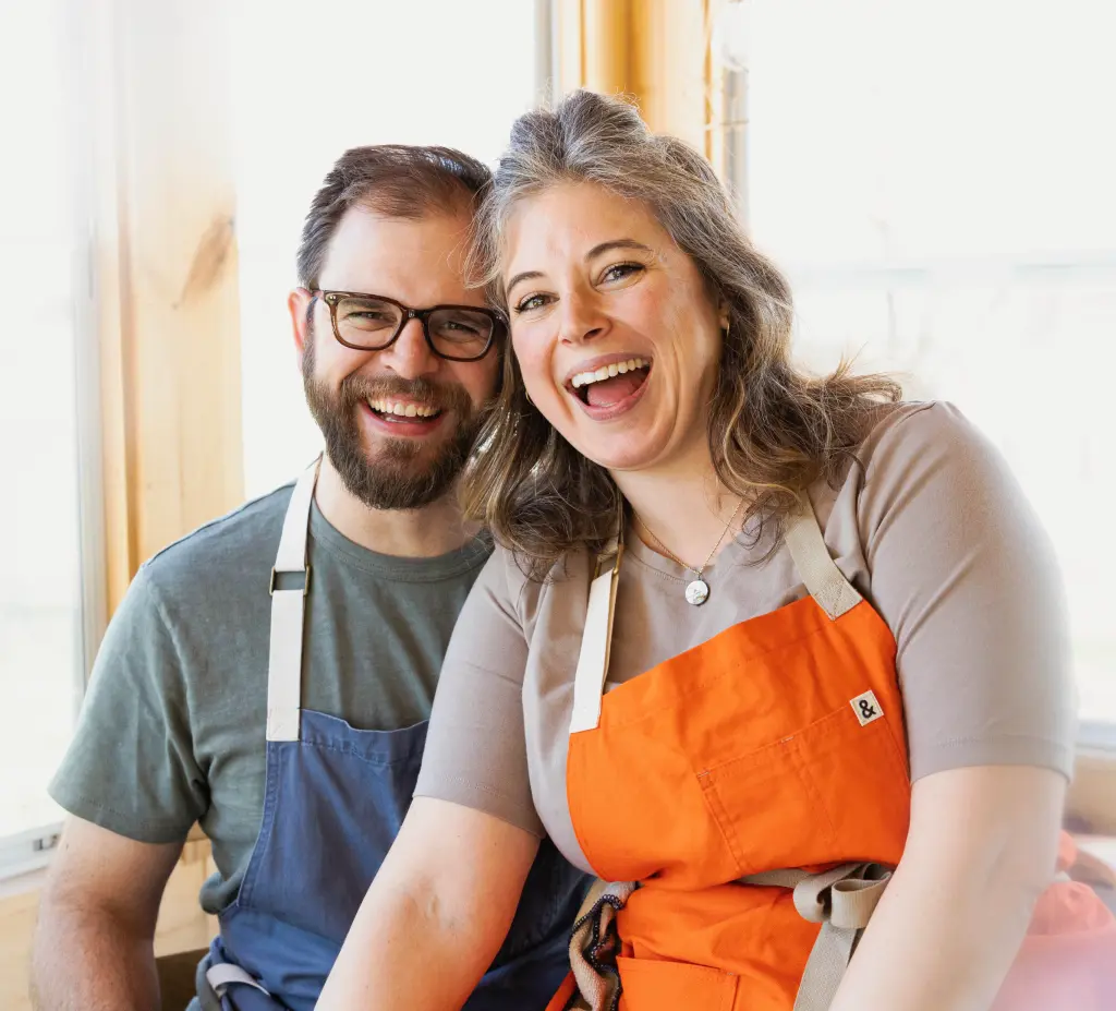 Husband and wife wearing aprons and smiling brightly
